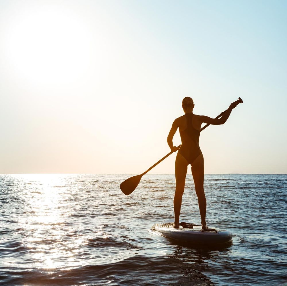 Silhouette di una persona in SUP in mare all'alba